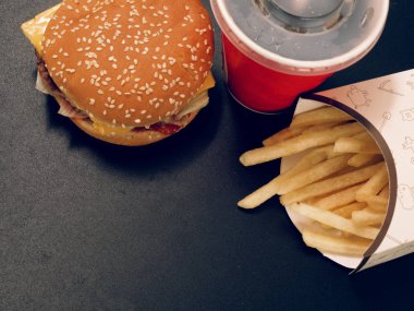 içki ve patates kızartması ve karanlık bir arka plan üzerinde burger