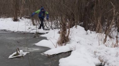 bir genç bir donmuş pond kışın yürür..