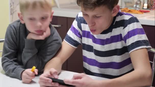 Barnen Leker Telefon Hemma Vid Bordet — Stockvideo