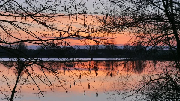 Röd solnedgång över vattnet i en sjö och by — Stockfoto