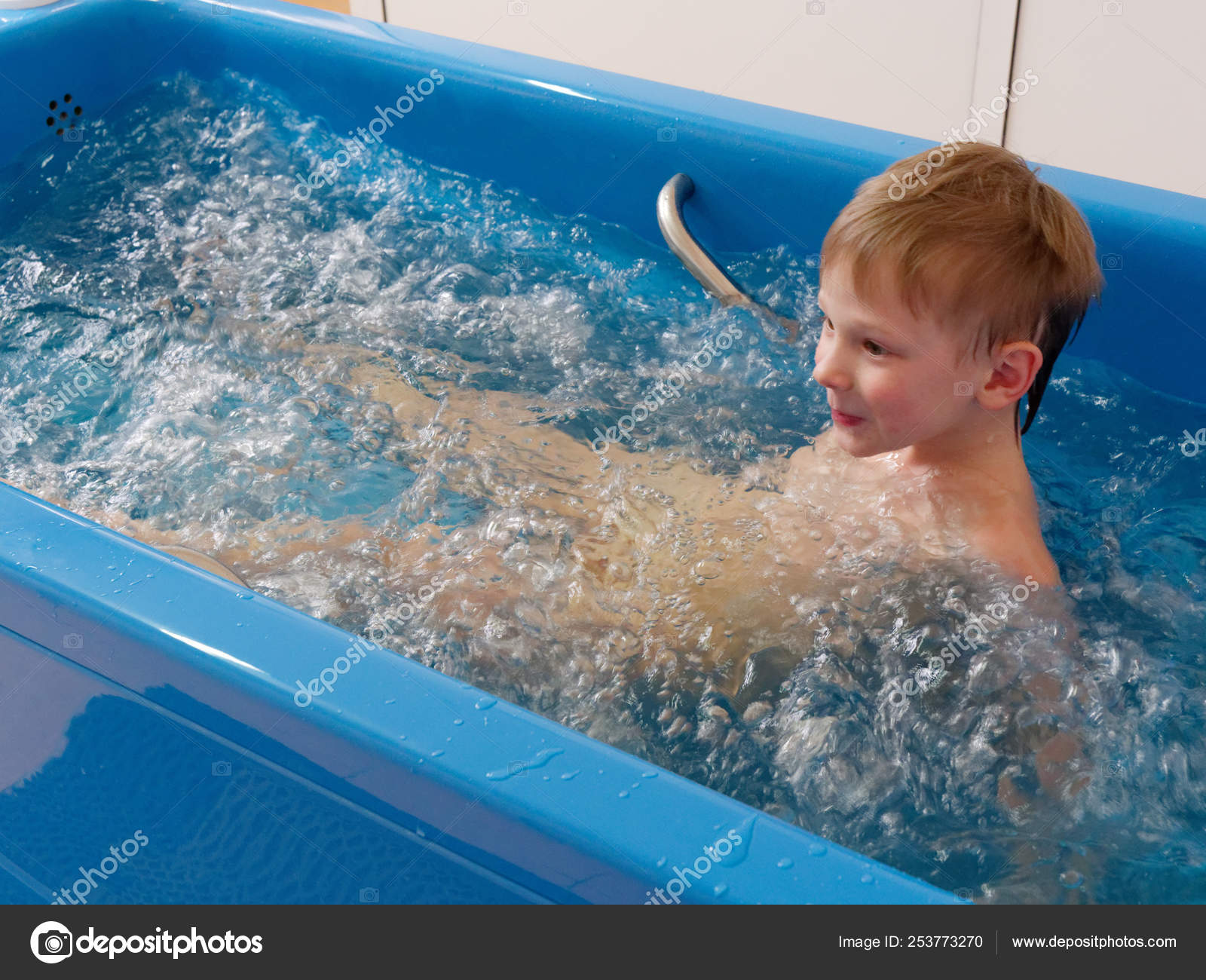Baby boy is taking a bath with bubbles. Jacuzzi bubble bath procedure. Stock Photo makALEX 253773270