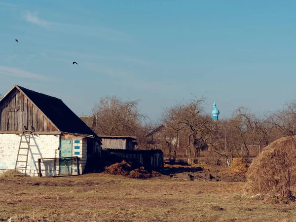 Leben im Dorf. Scheunenhof und Kirche am Horizont — Stockfoto