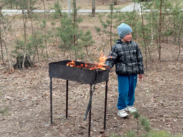 A boy with a poker at the brazier. cooks — Stock Photo, Image