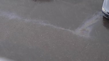 asfalt üzerine sağanak yağmur yağıyor. su üzerinde yağ lekeleri