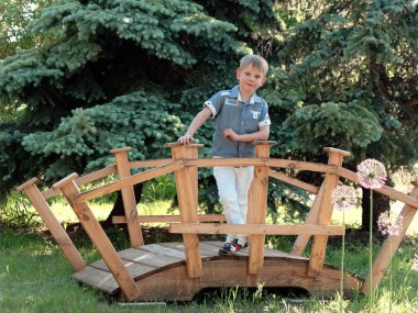 6 yaşında bir çocuk güzel bir dekoratif köprü üzerinde duruyor.