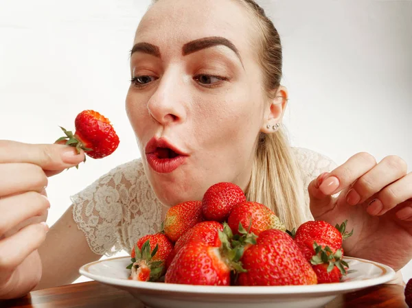 Mädchen eifrig essen Erdbeeren auf weißem Hintergrund. — Stockfoto