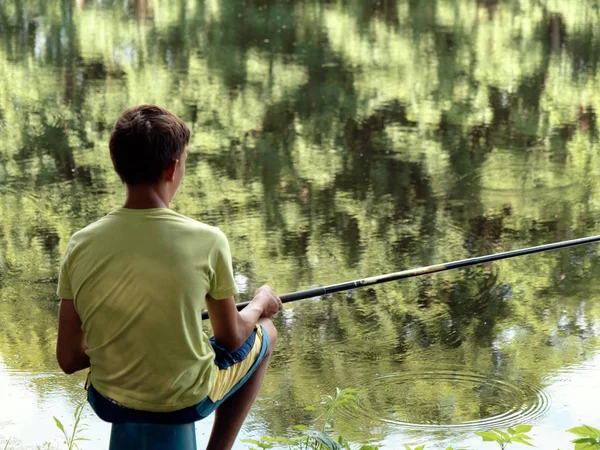 Dítě v pubertě chytí rybářské tyčinky na rybníčku. — Stock fotografie