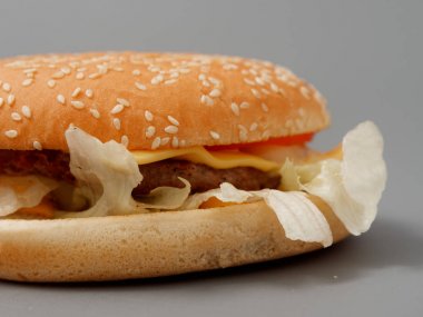 gri arka plan üzerinde pirpirit peynir domates lahana ile büyük burger