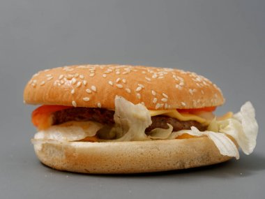 gri arka plan üzerinde pirpirit peynir domates lahana ile büyük burger