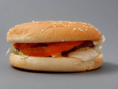 gri arka plan üzerinde pirpirit peynir domates lahana ile büyük burger