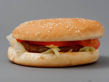 gri arka plan üzerinde pirpirit peynir domates lahana ile büyük burger