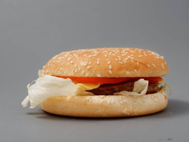 gri arka plan üzerinde pirpirit peynir domates lahana ile büyük burger