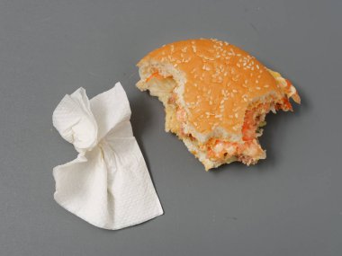 gri bir arka plan üzerinde pirlet peynir ve domates ile ısırılan büyük burger