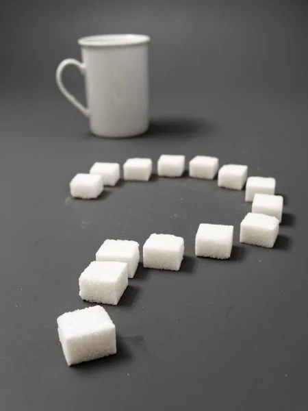 Witte suiker en vraagteken op een grijze achtergrond — Stockfoto