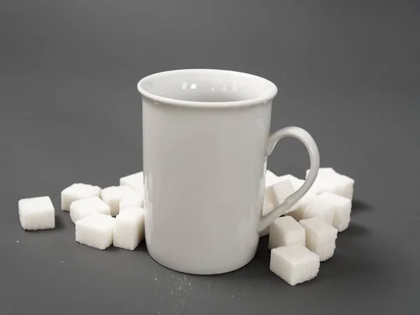 Refined sugar lump white and white cup on a gray background — Stock Photo, Image