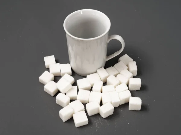 Refined sugar lump white and white cup on a gray background — Stock Photo, Image