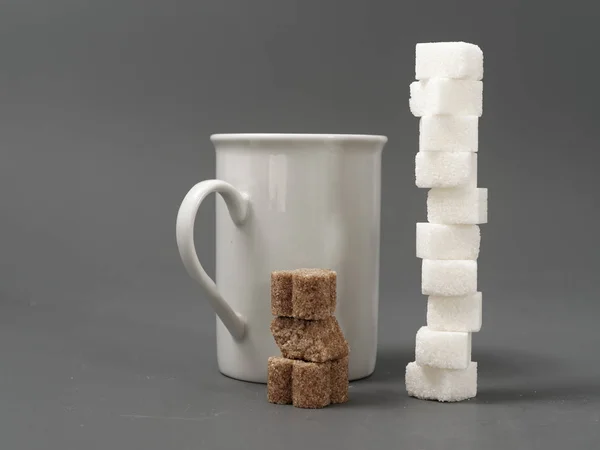 Verfijnde suiker knobbel witte en witte beker op een grijze achtergrond — Stockfoto
