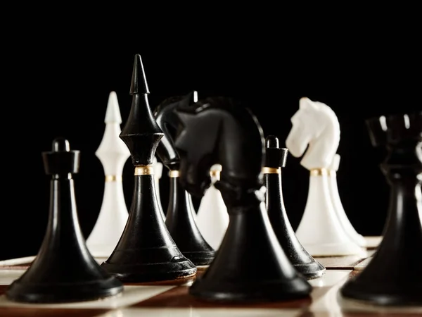 Peças de xadrez no tabuleiro em um fundo preto — Fotografia de Stock