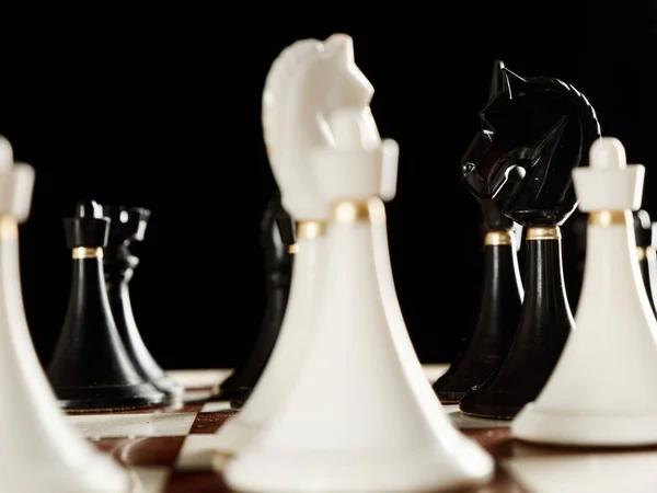 Шахматные фигуры на доске на черном фоне — стоковое фото