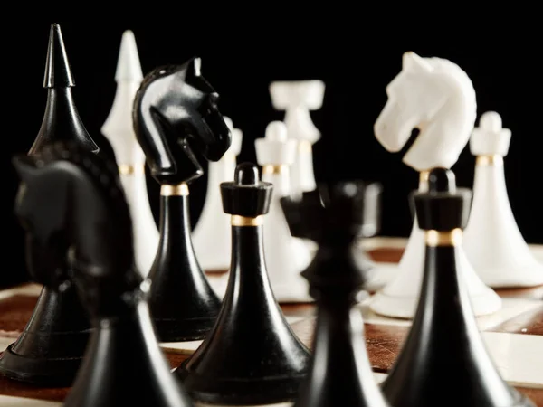 Chess pieces on the board on a black background — Stock Photo, Image