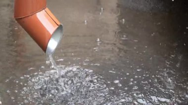 Yağmurda drenaj borusu. Su birikintisi içine akar