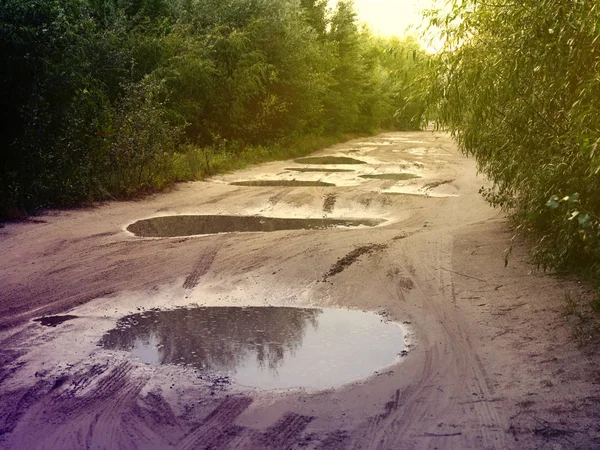 Akşam su birikintileri ile Dirt yoksul ülke yolu — Stok fotoğraf