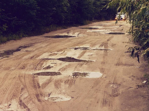 Akşam su birikintileri ile Dirt yoksul ülke yolu — Stok fotoğraf