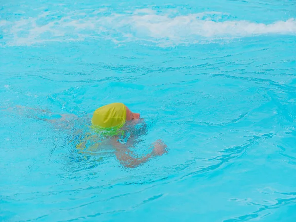 Niño nada en una piscina con agua azul —  Fotos de Stock