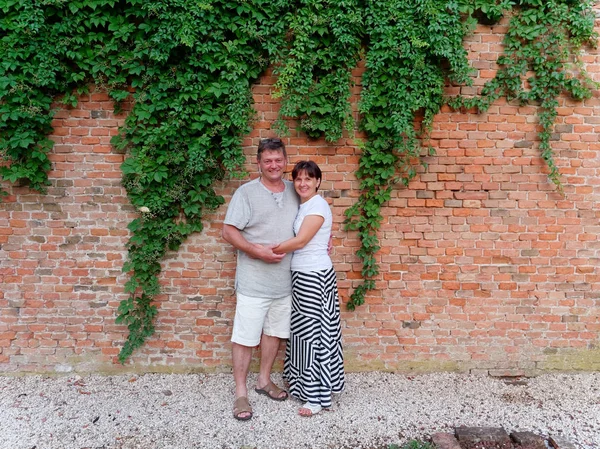 Hombre y mujer en el fondo de una pared de ladrillo con hiedra verde — Foto de Stock