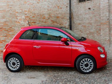 Mantova, İtalya - 10 Ağustos 2019: Kırmızı Fiat 500 arabası duvara park etti. Tarihi binalar.