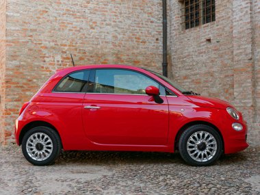 Mantova, İtalya - 10 Ağustos 2019: Kırmızı Fiat 500 arabası duvara park etti. Tarihi binalar.