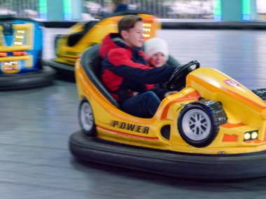 Çocuklar çocuk eğlencesine biniyor elektrikli arabalara biniyor.