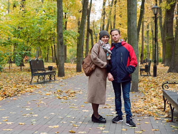Anne genç oğluyla birlikte sonbahar sarı parkında — Stok fotoğraf