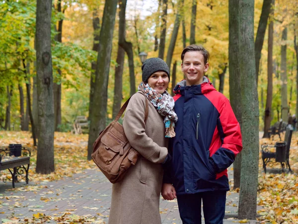 Anne genç oğluyla birlikte sonbahar sarı parkında — Stok fotoğraf