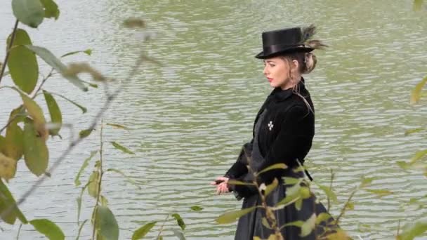 秋の水を背景に黒いドレスを着た女の子 — ストック動画