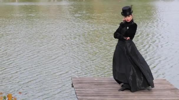 穿着黑色衣服的女孩站在水的背景上 — 图库视频影像