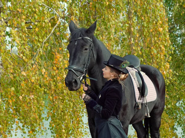 Ragazza in un abito nero con un cavallo nero primo piano — Foto Stock