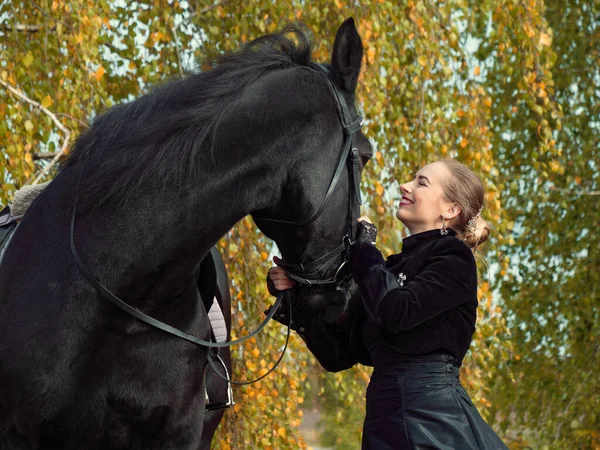 Ragazza in un abito nero con un cavallo nero primo piano — Foto Stock