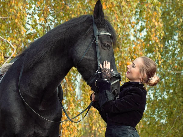 Ragazza in un abito nero con un cavallo nero primo piano — Foto Stock