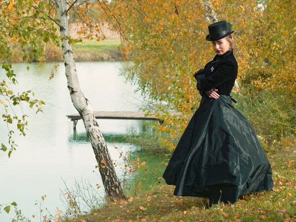 Menina em um vestido preto nos ramos de vidoeiro no outono — Fotografia de Stock