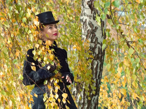 Chica en un vestido negro en las ramas de abedul en otoño — Foto de Stock