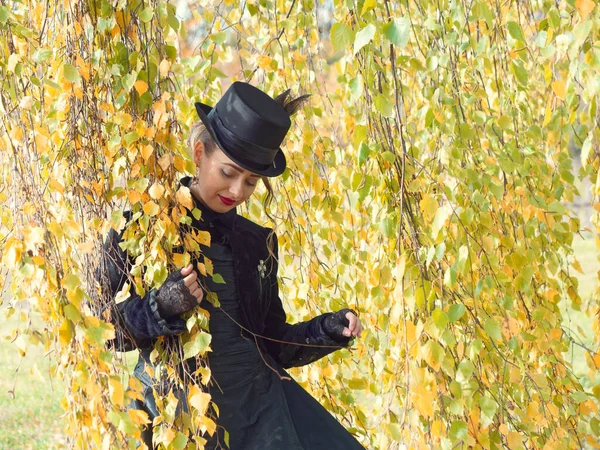 Mädchen im schwarzen Kleid in den Birkenzweigen im Herbst — Stockfoto