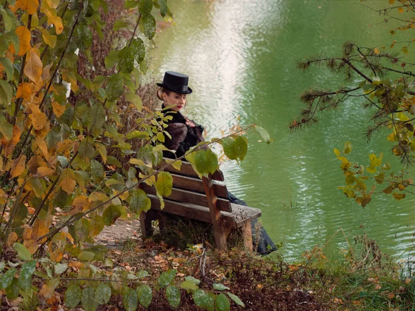 Dívka v černých šatech na pozadí vody na podzim — Stock fotografie