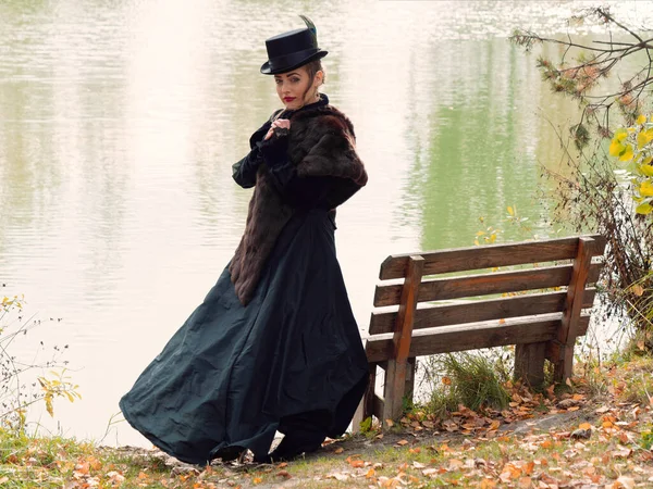 秋の水を背景に黒いドレスを着た女の子 — ストック写真