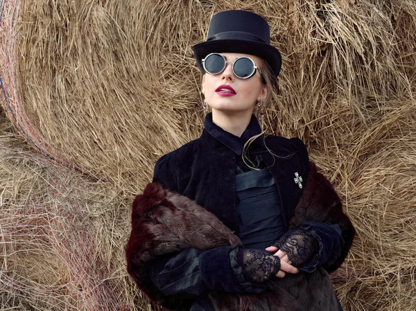 Menina em um vestido preto em um fundo de palha no outono — Fotografia de Stock