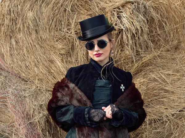 Menina em um vestido preto em um fundo de palha no outono — Fotografia de Stock