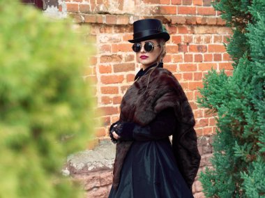 Sonbaharda duvarın arkasında siyah elbiseli bir kız.