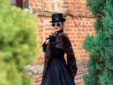 Sonbaharda duvarın arkasında siyah elbiseli bir kız.