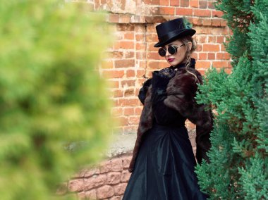 Sonbaharda duvarın arkasında siyah elbiseli bir kız.