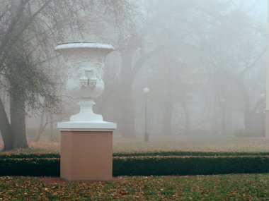 Sonbaharda sisin içinde beyaz vazo heykeli. Gomel, Belarus